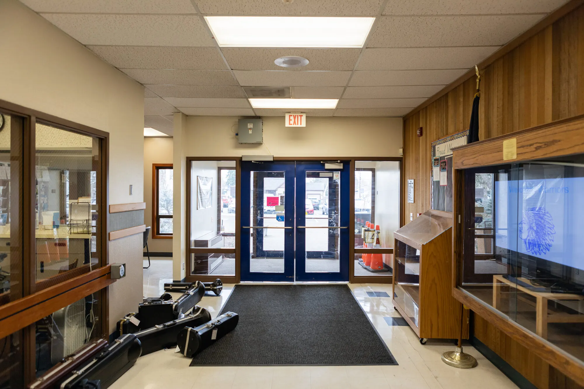 The front entry at Amity Elementary School, with blue double doors and a display case for the Warriors.